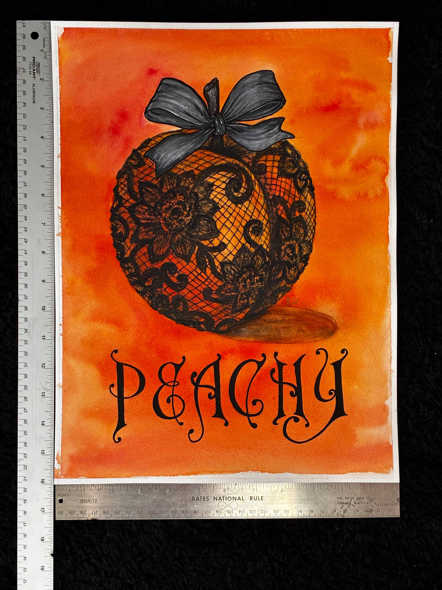 A square art print featuring a black lace peach ornament with a dark bow on an orange watercolor background, with the word 'PEACHY' in black decorative script below. The print is photographed flat against a black background with metal rulers visible along the left and bottom edges.