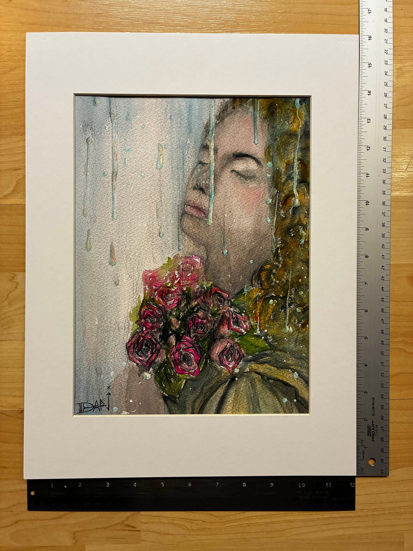 Artistic depiction of a person with flowers in front of a window, framed and displayed on a wooden surface.