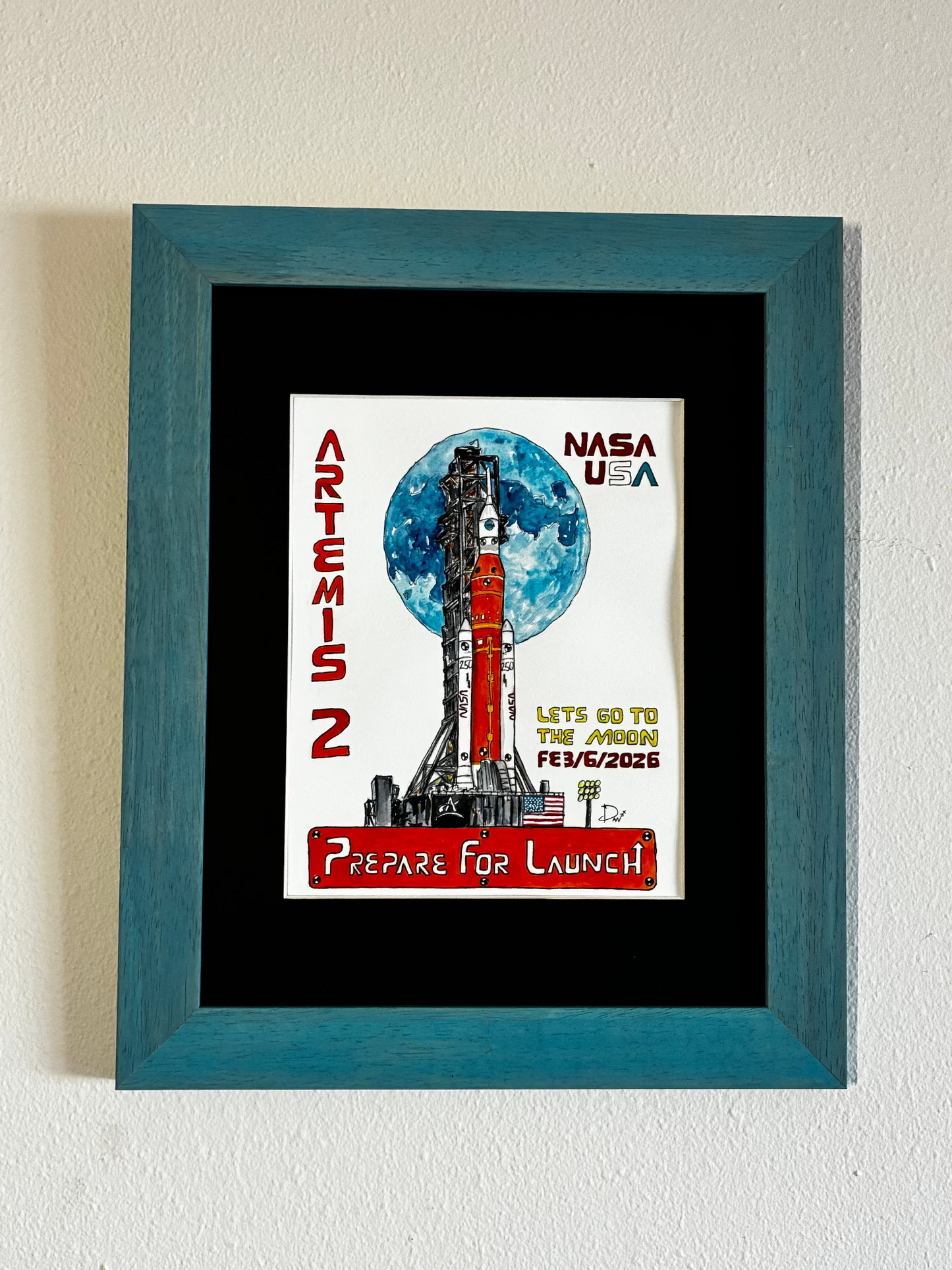 Framed watercolor painting of NASA Artemis 2 mission on a white wall