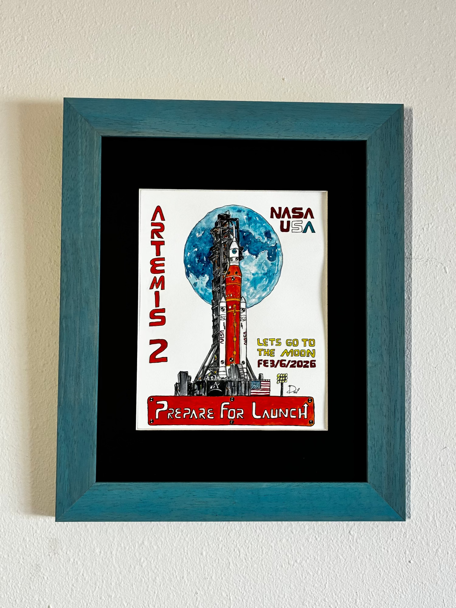 Framed watercolor painting of NASA Artemis 2 mission on a white wall
