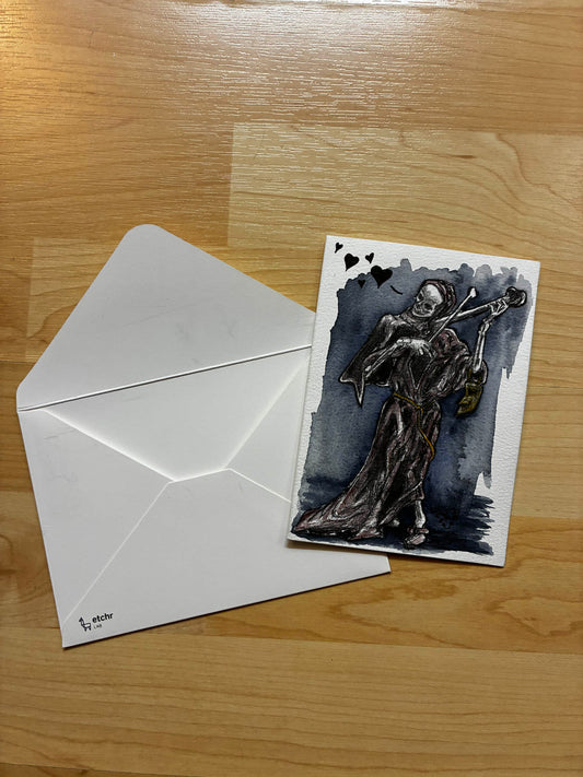 Greeting card with skeleton design and envelope on a wooden surface