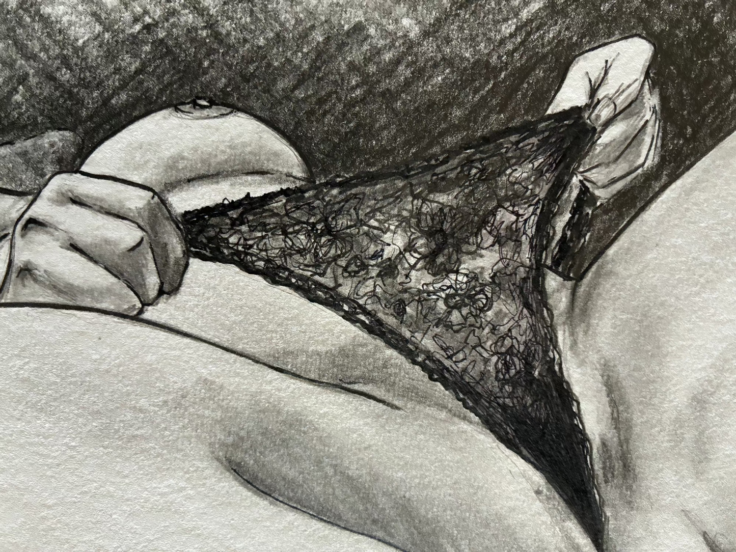 Black lace underwear held by a hand against a neutral background