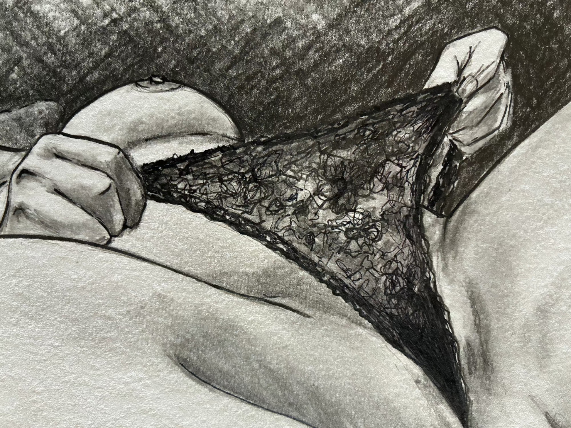 Black lace underwear held by a hand against a neutral background