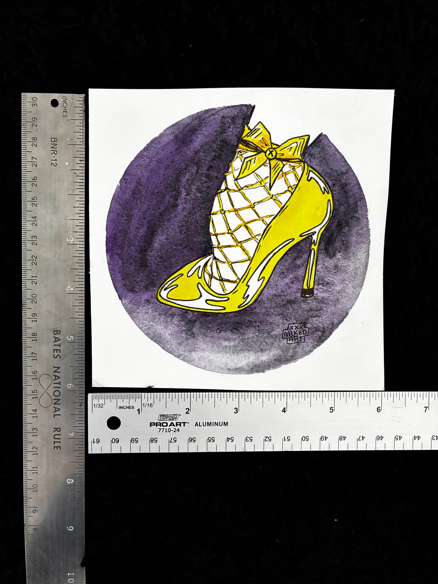 Yellow high-heeled shoe with a bow on a purple circle, next to two rulers for scale.
